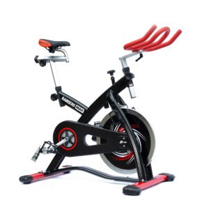 Imagen de una bicicleta tipo indoor bike de color negro con detalles en rojo. Se muestran los ajustes del manubrio y del asiento, tanto en altura como en distancia. El asiento es similar al de las bicicletas de carrera.