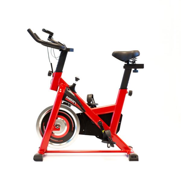 Bicicleta indoor de color rojo marca Randers, vista de perfil. Asiento y manubrio negros. Disco de inercia plateado. Regulador de altura y distancia del asiento visible. Regulador de altura del manubrio visible. Tablero negro. Rosca para ajuste de patas traseras visible.